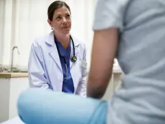 Lekarka w kitlu rozmawia z pacjentem. Dowiedz się, jak zmienić lekarza rodzinnego, gdy potrzebujesz nowej opieki medycznej.