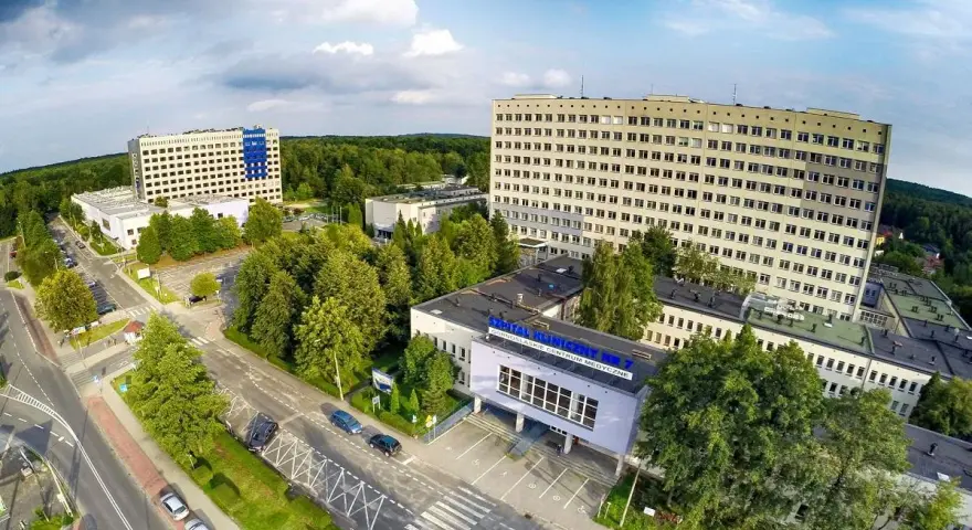Widok z lotu ptaka na kompleks budynków szpitalnych otoczony zielenią.