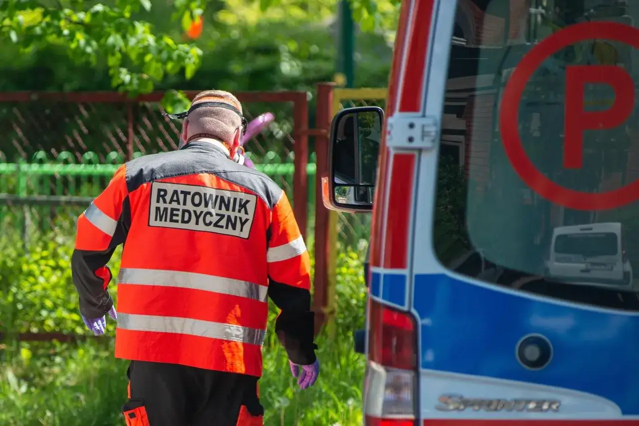 Ratownik medyczny w pomarańczowej kamizelce przy karetce. Zastanawiasz się, ile zarabia ratownik medyczny?